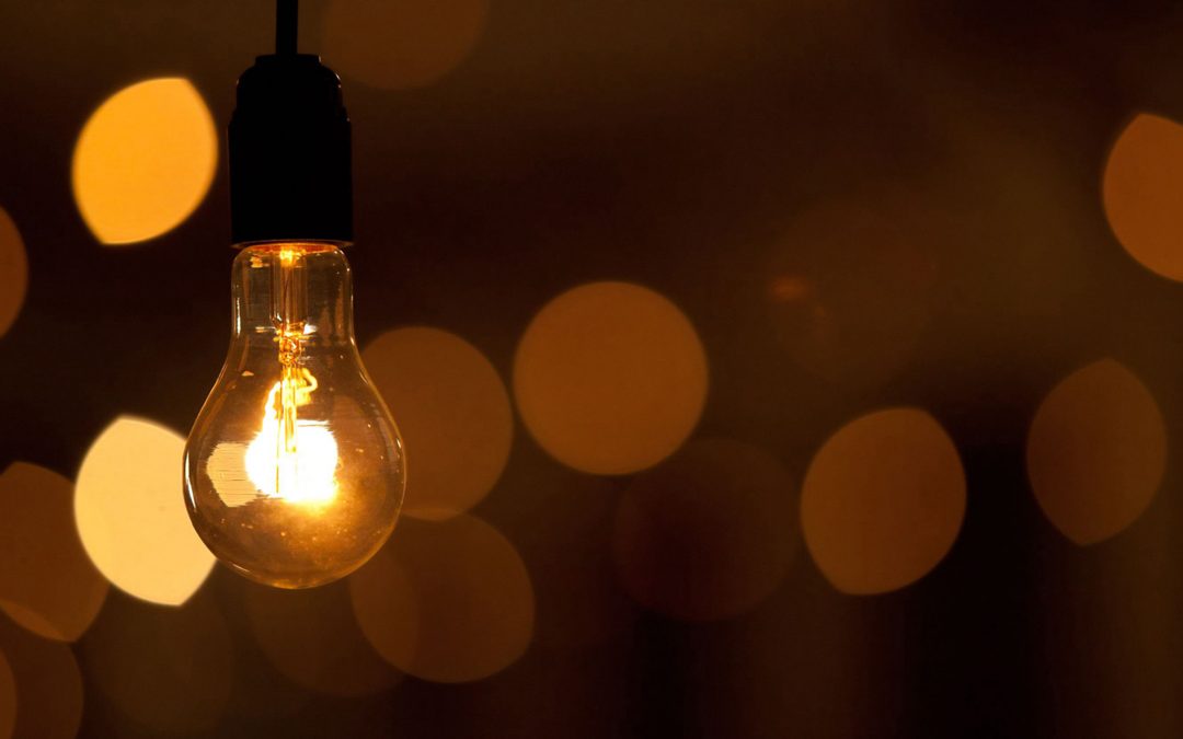 Burning bulb shines weakly on the background blurred yellow lights