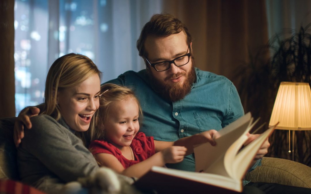 Family in warm living room reading a book